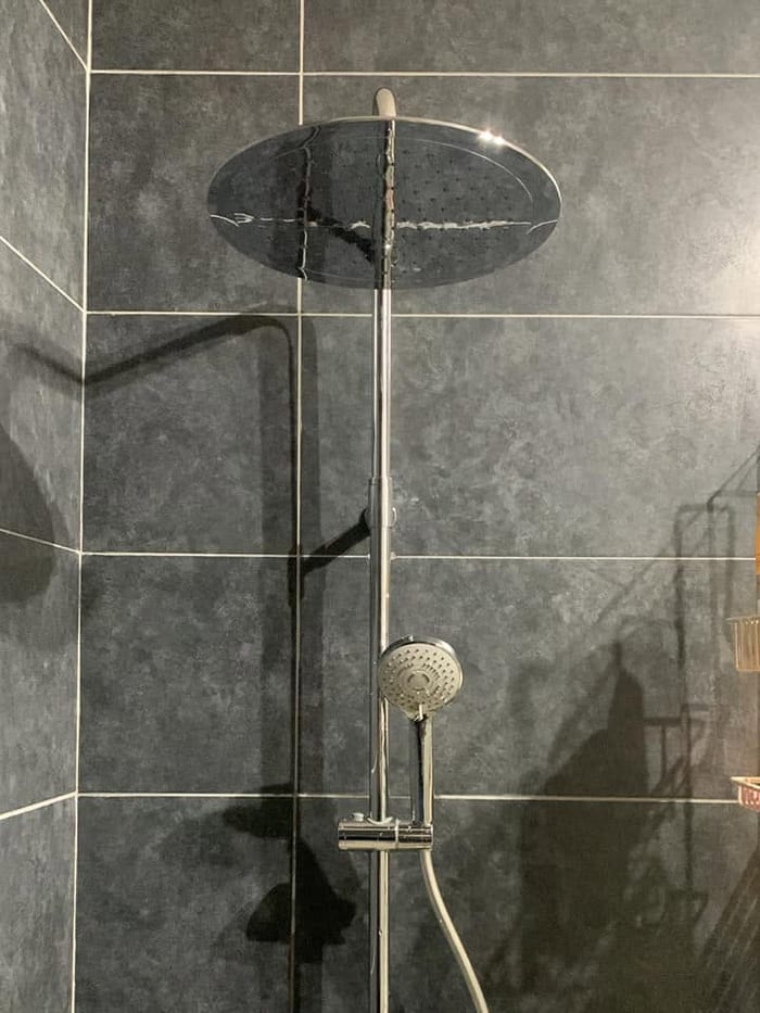 Colonne de douche chromée posée sur un mur en ardoise